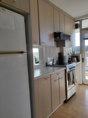 Enjoy cooking in this well-equipped kitchen with an oven, stainless steel refrigerator, and range hood.