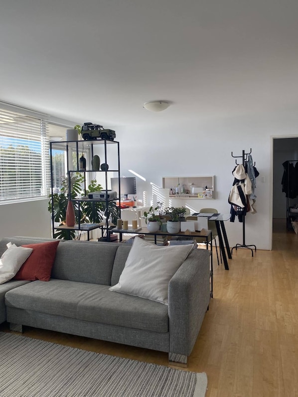 Relax in this stylish living space with a grey sofa, glass coffee table, and lush greenery.