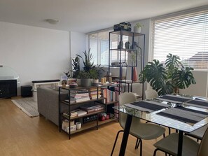 Relax in this stylish living room with a glass-top dining table, comfortable sofa, and a large potted plant.
