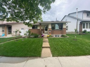 A two-story house with a front porch, a brick foundation, and a well-maintained lawn.