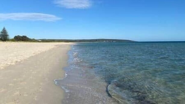 A beach with clear water and a sandy shore.