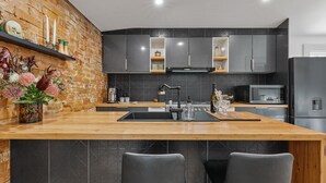 Una cucina moderna con isola in legno, mobili scuri e una parete decorata con mattoni.