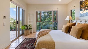 Ein Schlafzimmer mit einem Bett, einem Fenster, einem Deckenventilator und Blick auf Grünflächen.