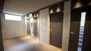 Un couloir moderne doté d’une grande fenêtre, d’une porte avec une fenêtre verticale et d’un ascenseur.