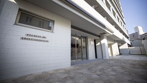 Un bâtiment moderne avec une entrée carrelée en pierre et une enseigne dans une langue étrangère.