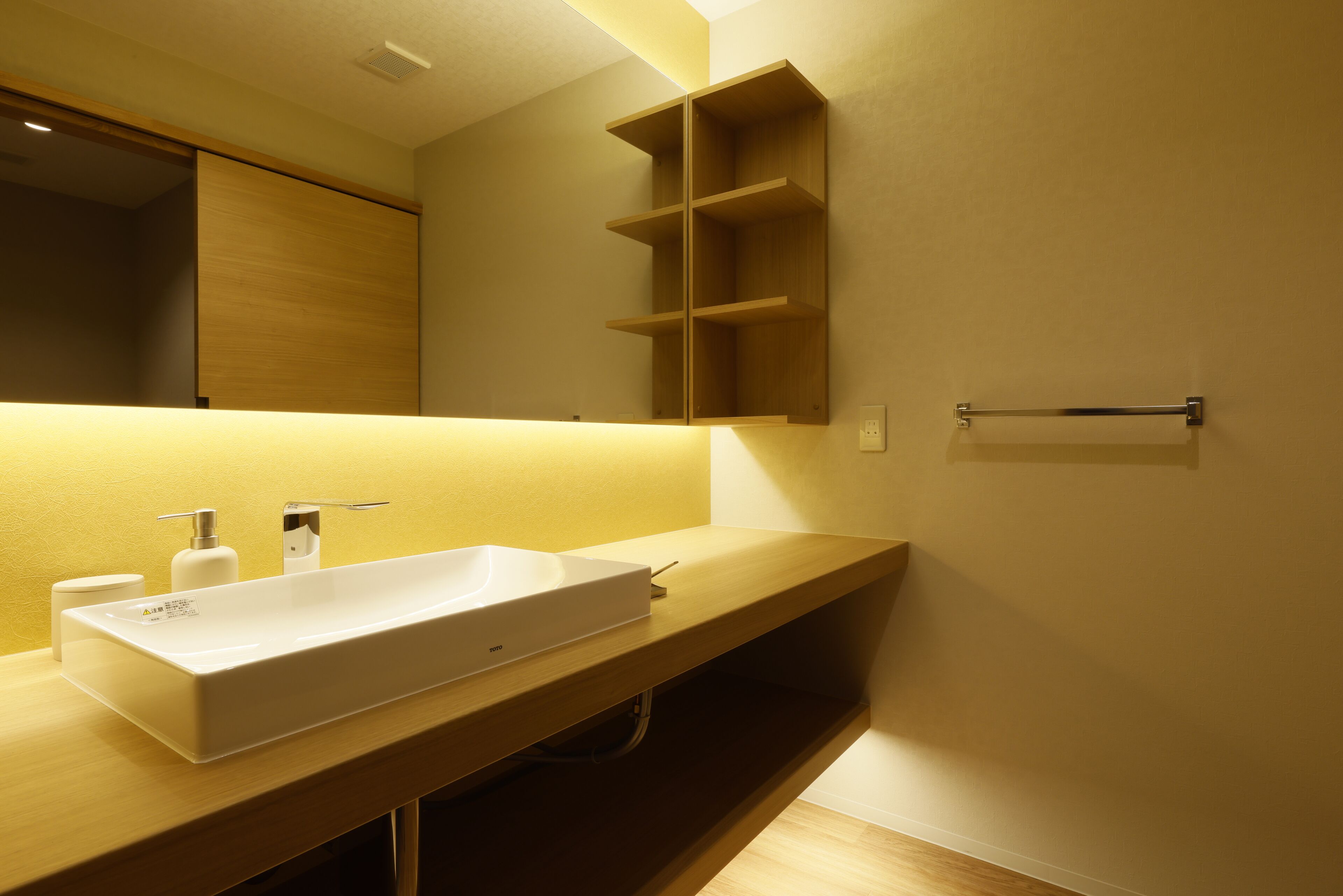 Un bagno moderno con un lavandino rettangolare grande, uno specchio e scaffali in legno.