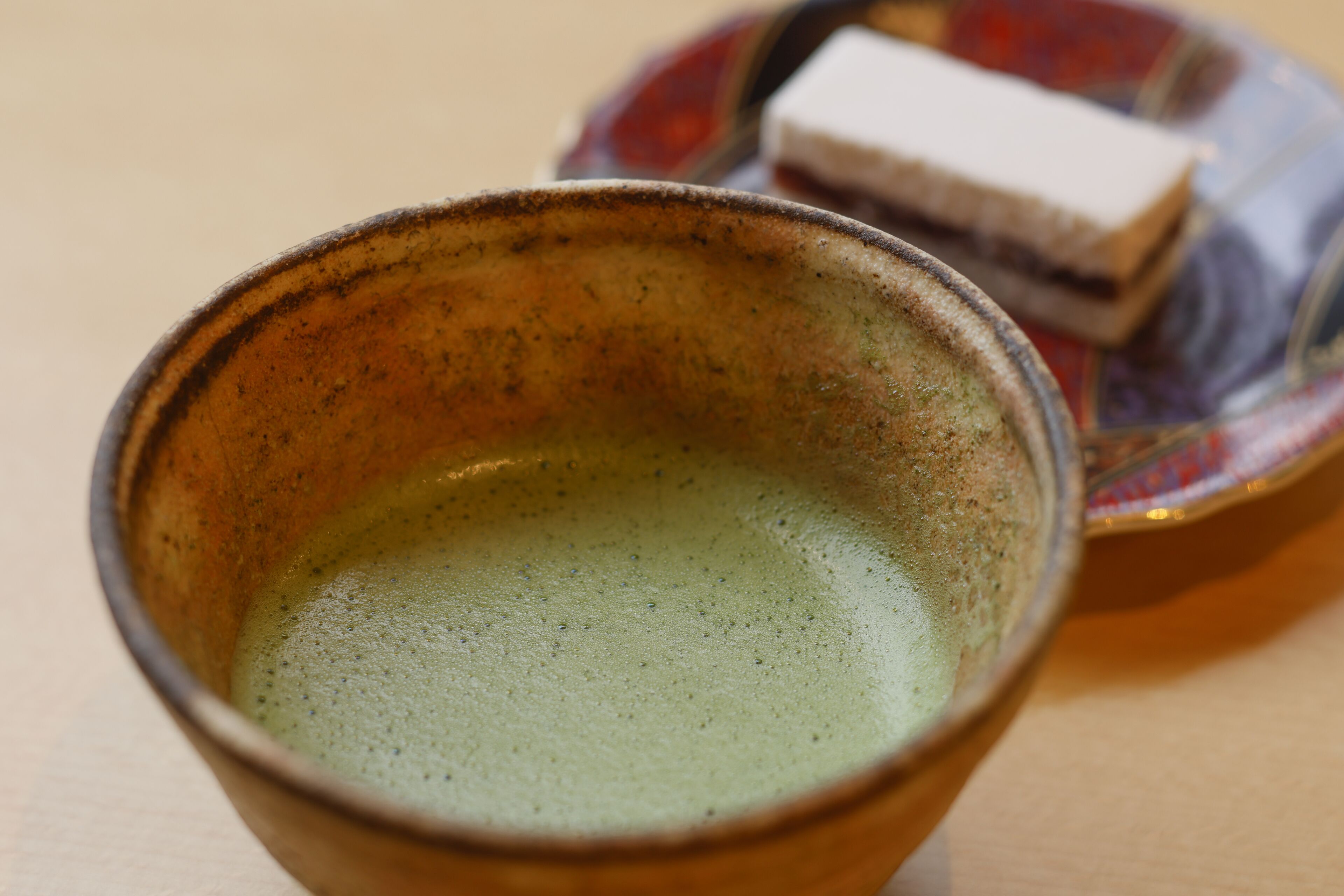 A ceramic cup with a greenish liquid, possibly tea, on a table.