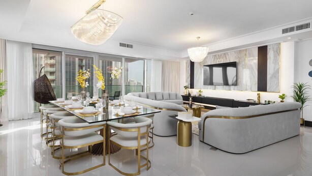 A modern living room with a glass dining table, white sofas, and a large TV. -  Maison Privee - Ultra Chic High-Floor Apt w/ Direct Burj Khalifa & Fountains Views (Dubai)