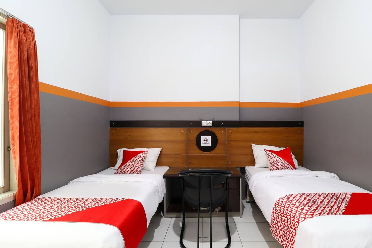 Une chambre d’hôtel avec deux lits, un bureau et une chaise.