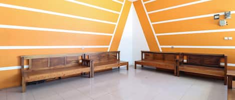 A room with two wooden benches against orange walls, a white ceiling, and a tiled floor.