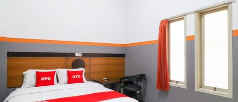Una habitación de hotel con cama, mesita de noche, una silla y una ventana con cortinas.
