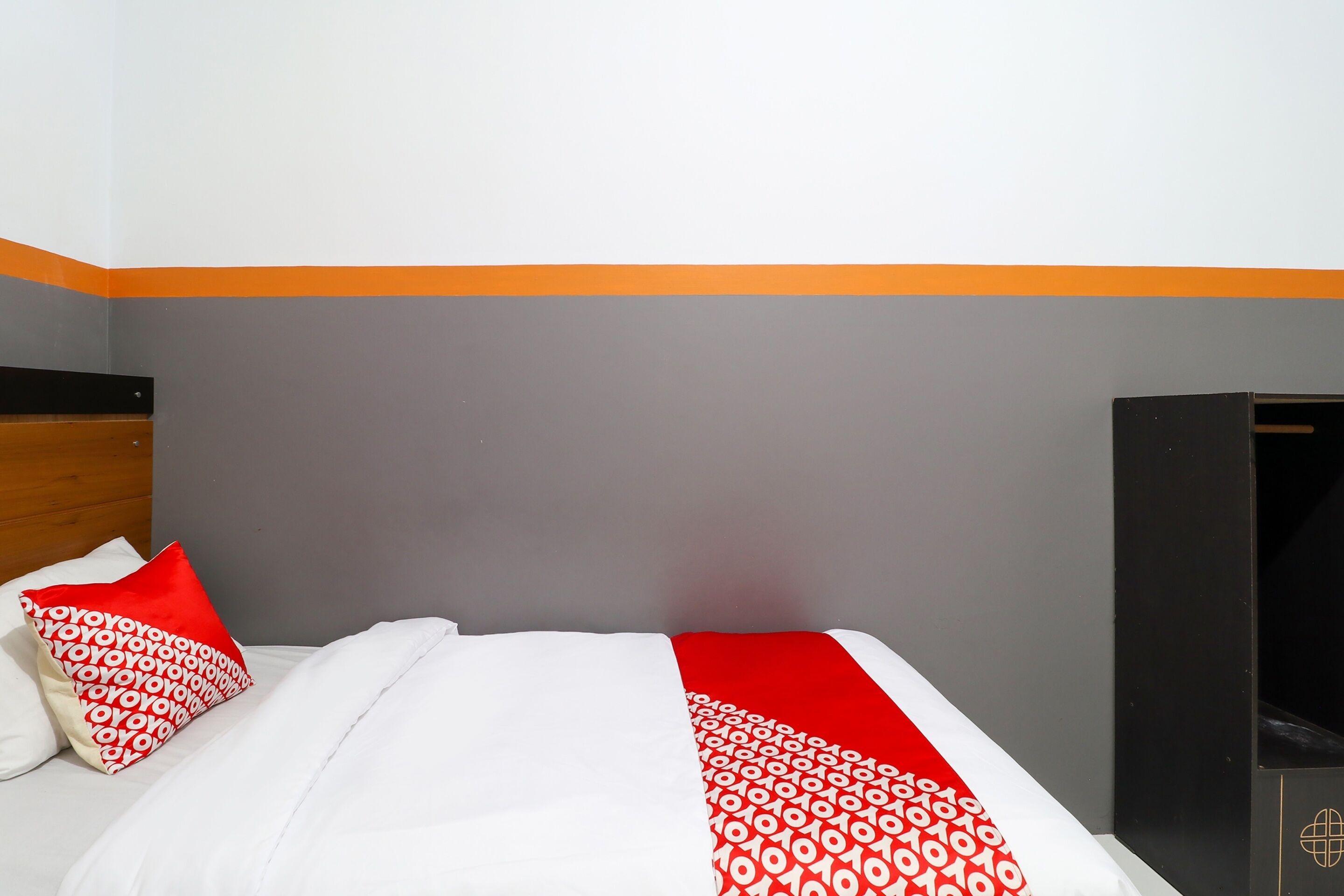 Hotellihuone, jossa on sänky, tyynyjä ja vaatekaappi.