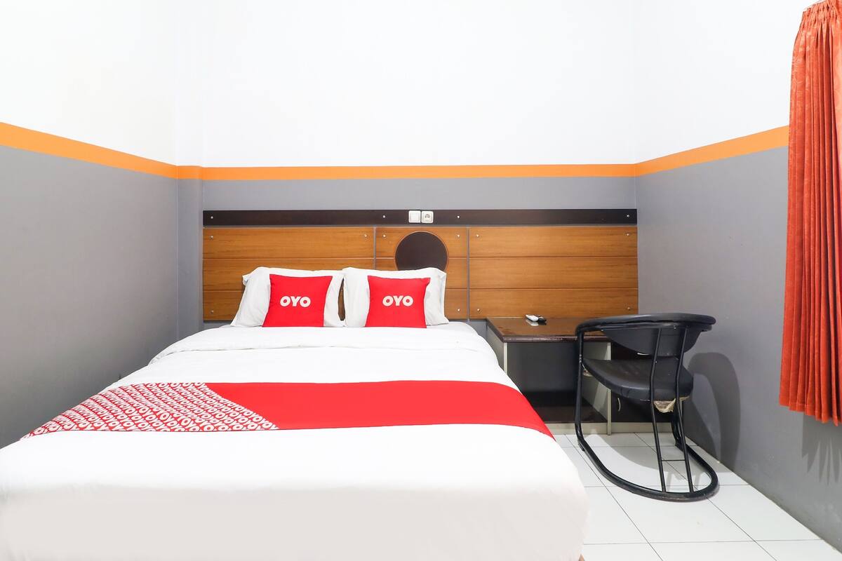 Une chambre d’hôtel avec un lit, un bureau et une chaise.