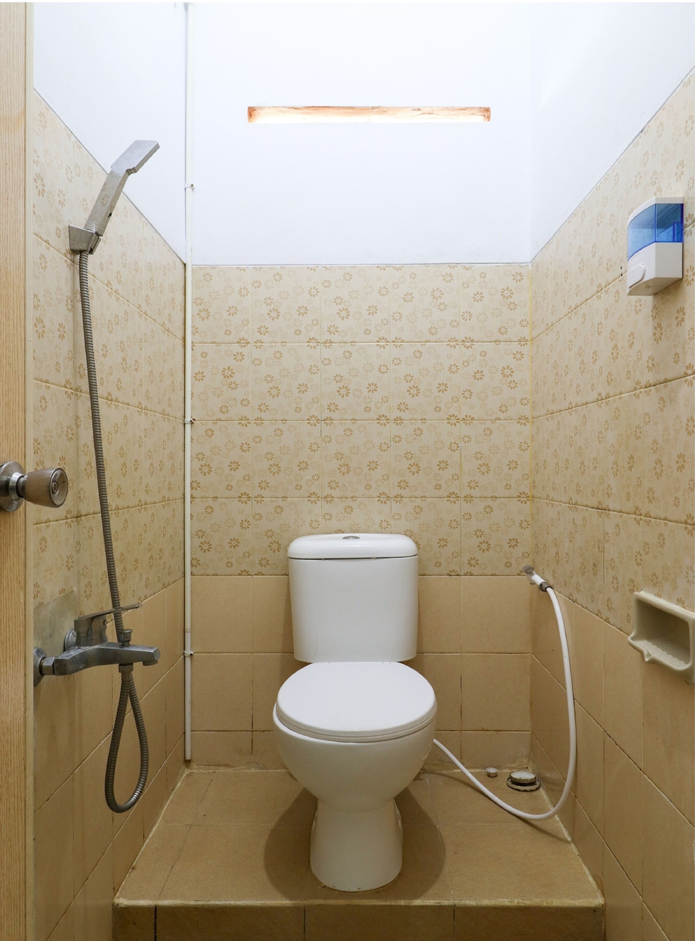 Un baño pequeño y funcional con inodoro, ducha y secador de manos.