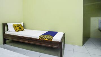 A single bed with a wooden frame, white bedding, and a yellow and blue pillow.