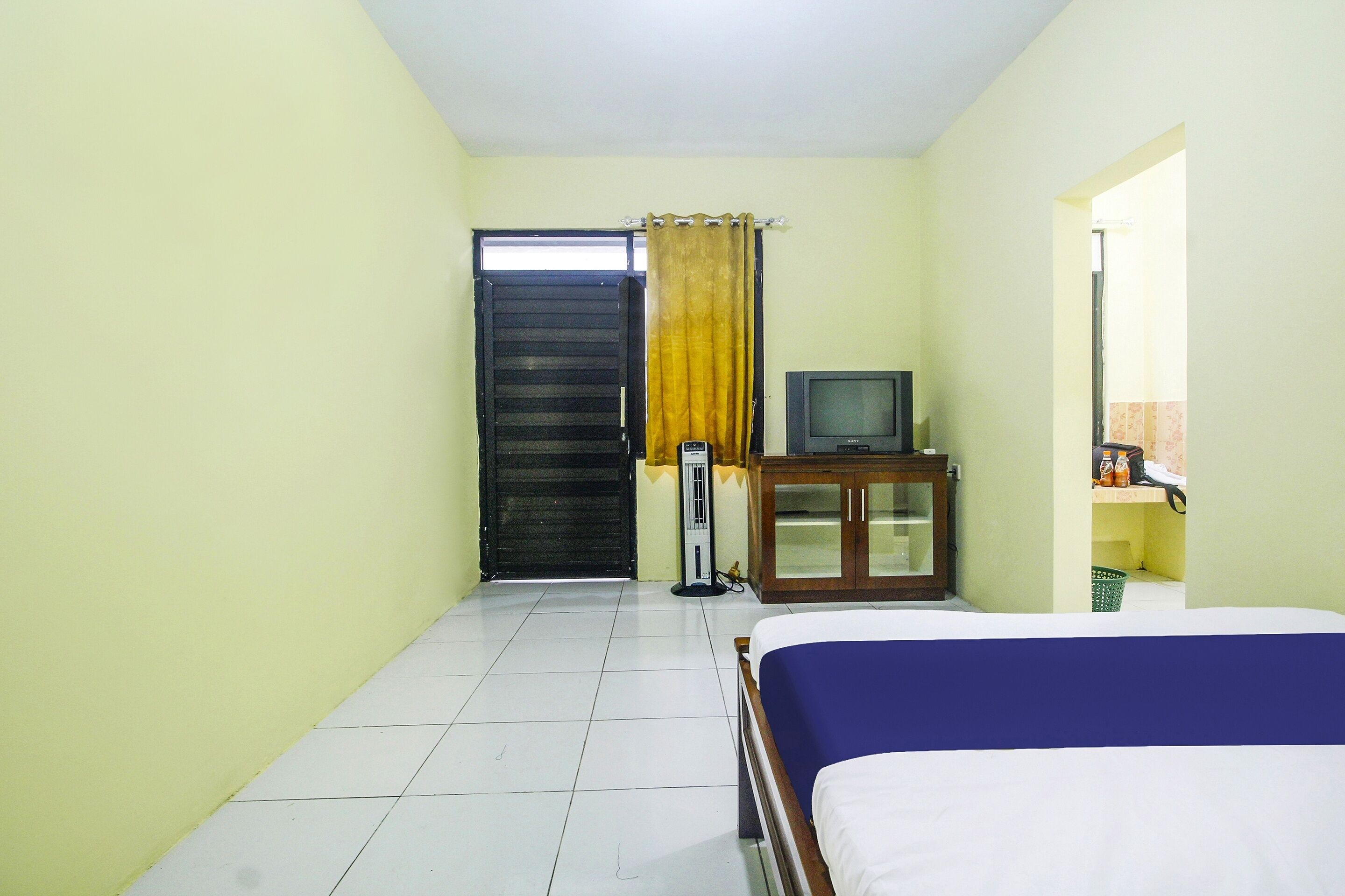 Un dormitorio con cama, televisor, armario y puerta.