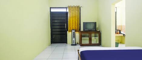 Un dormitorio con cama, televisor, armario y puerta.