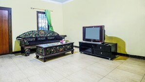 A living room with a sofa, a coffee table, and a television on a stand. - OYO Life 91606 Nadin Guest House Syariah (Garut)