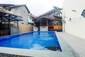 A rectangular swimming pool with a tiled edge, surrounded by a brick wall and a wooden deck. - OYO Life 91606 Nadin Guest House Syariah (Garut)