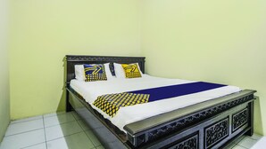 A bed with a dark wooden frame, white bedding, and patterned pillows in a room with yellow walls and tiled flooring. - OYO Life 91606 Nadin Guest House Syariah (Garut)