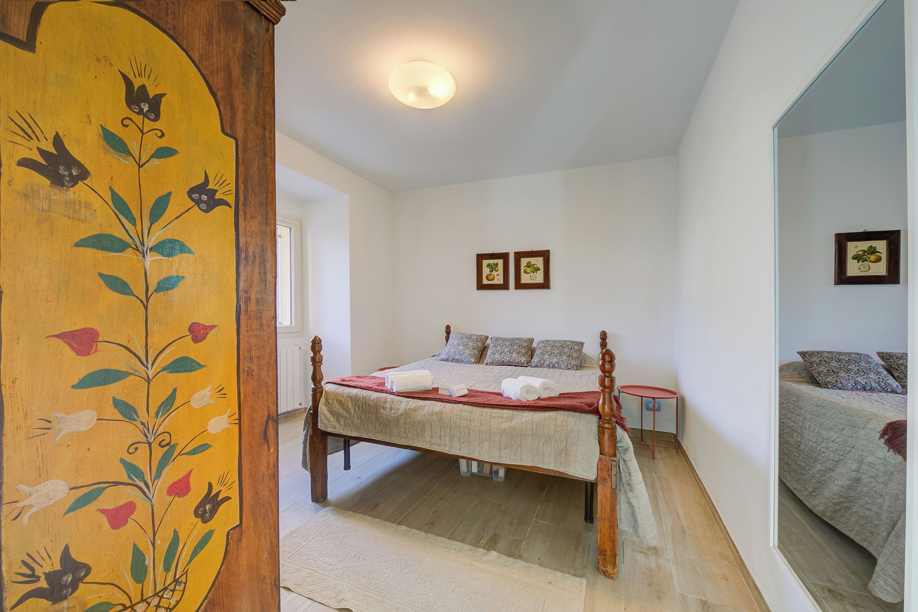 A bedroom with a bed, a small table, and a mirror.
