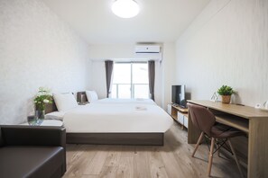 A modern hotel room with a large bed, a desk, a chair, a TV, and a potted plant. - Seiryu Tsutenkaku (Osaka)