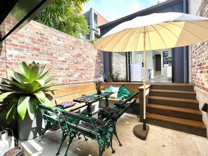 A patio area with a brick wall, a wooden staircase, and outdoor furniture. - Paddington Dream - an Urban Oasis (Paddington)