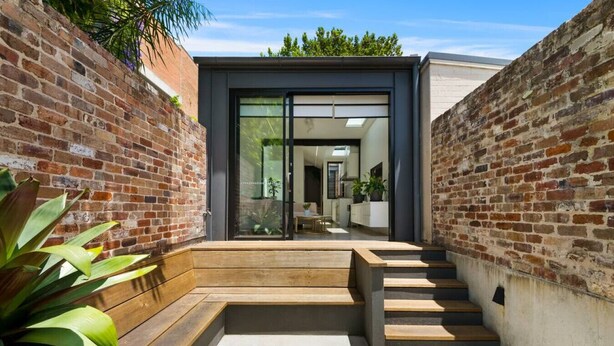 A modern house with a brick exterior, a wooden staircase leading to a glass door, and a concrete patio. - Paddington Dream - an Urban Oasis (Paddington)