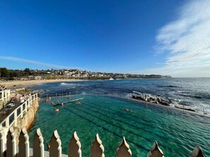 A coastal scene with clear blue waters, a pier, and a town in the background. - Paddington Dream - an Urban Oasis (Paddington)