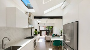 A modern kitchen with a skylight, a dining area with a table and chairs, and a large refrigerator. - Paddington Dream - an Urban Oasis (Paddington)