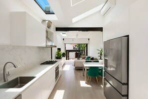 Een moderne keuken met een inbouwfornuis, een roestvrijstalen koelkast en een dakraam.