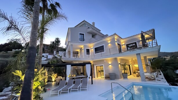Ein zweigeschossiges Haus mit Pool, Sitzgelegenheit im Freien und einem Balkon.