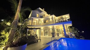 Ein zweistöckiges Haus mit Swimmingpool, Außenbereich zum Sitzen und einem Balkon.