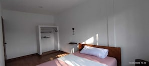 Ein Schlafzimmer mit einem Bett, einem Kleiderschrank und einer kleinen Ablagefläche.