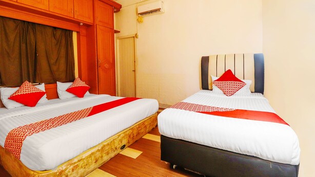 A hotel room with two beds, wooden headboards, and a red and white bedspread. - OYO 91607 Steze Guest House Syariah (Jambi)