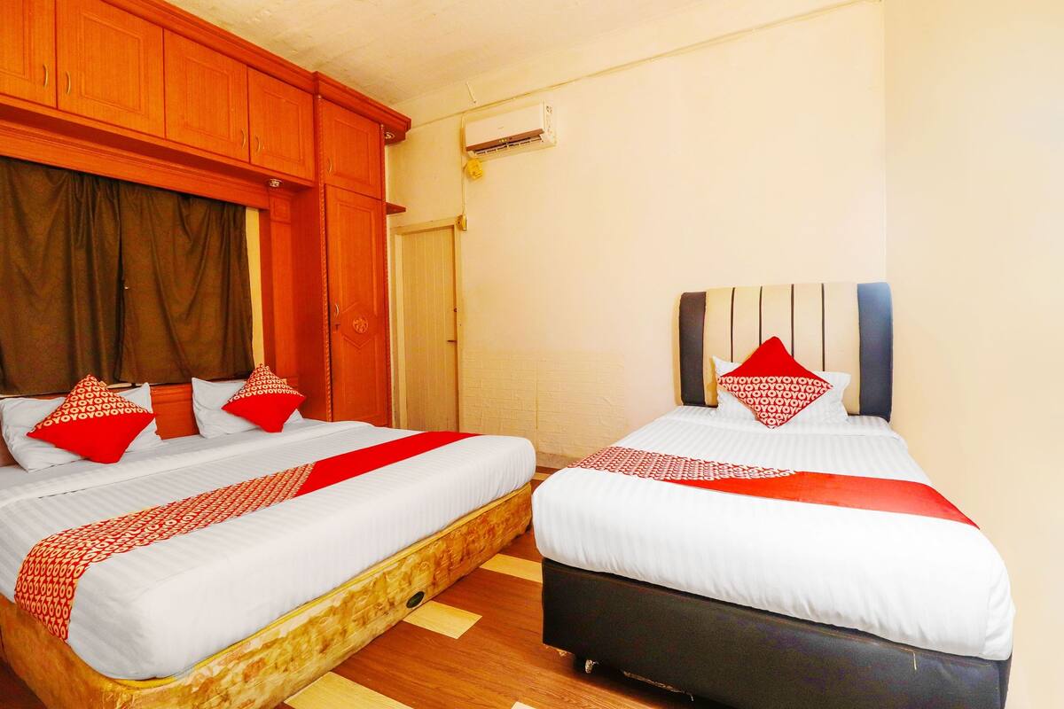 A hotel room with two beds, wooden headboards, and a red and white bedspread.