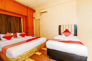 Habitación de hotel con dos camas, cabeceros de madera y colcha roja y blanca.