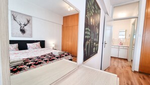A bedroom with a bed, a nightstand, a wooden wardrobe, and a poster on the wall.