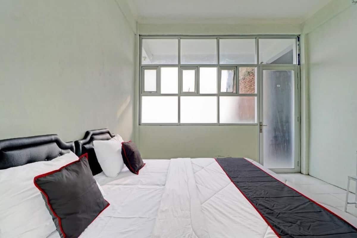 Une chambre à coucher avec un lit, des oreillers, une fenêtre et une porte.