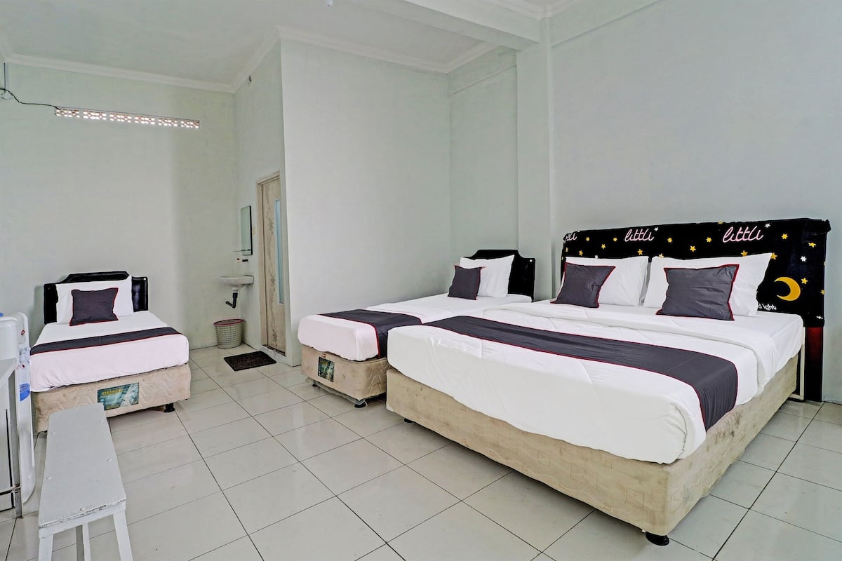 Une chambre d’hôtel avec deux lits, une petite table, un miroir et une table de chevet.