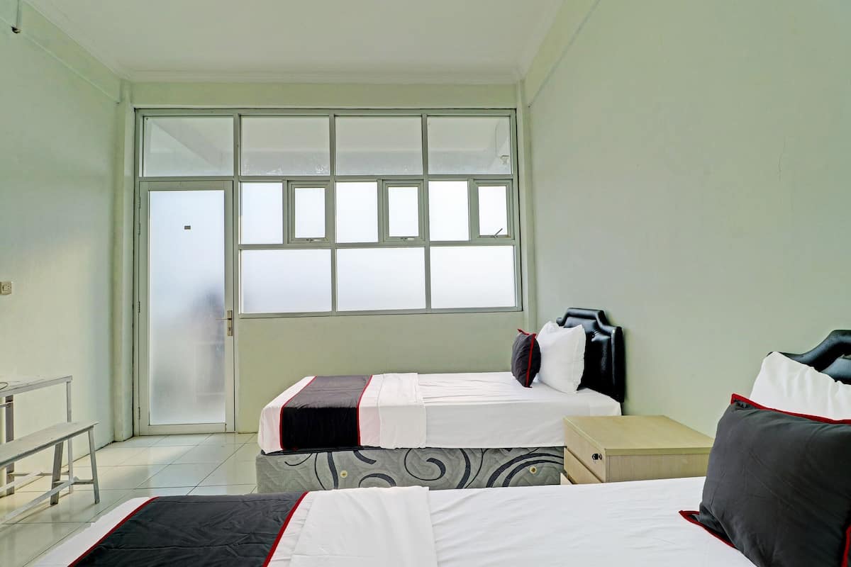 Une chambre d’hôtel avec deux lits, un banc et une grande fenêtre.