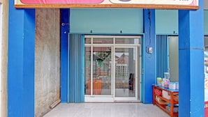 A storefront with a blue exterior, a glass door, and a small table with items on it. - OYO 91960 Fariza House Syariah  (Kendal)