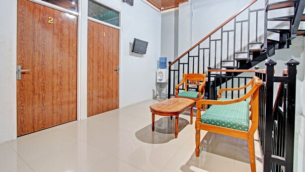 A hotel lobby with wooden doors, a staircase, and seating area. - OYO 91960 Fariza House Syariah  (Kendal)