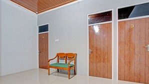 A room with a wooden bench, three wooden doors numbered 3, 4, and 5, and a tiled floor. - OYO 91960 Fariza House Syariah  (Kendal)