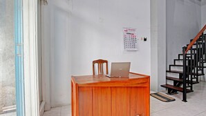 A wooden desk with a laptop, a chair, and a calendar on the wall. - OYO 91960 Fariza House Syariah  (Kendal)