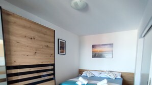 A bedroom with a bed, wooden wardrobe, and a painting on the wall.