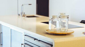 A kitchen counter with a wooden tray holding two glass jars, a stainless steel faucet, and a white cabinet. - CARTAMAR by Buenavilla | Refurbished villa with lots of outdoor space (Tías)