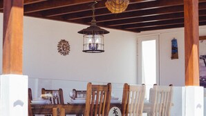 A dining area with wooden chairs and a table set for a meal, a hanging lantern, and a wall decoration. - CARTAMAR by Buenavilla | Refurbished villa with lots of outdoor space (Tías)