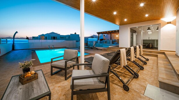 A rooftop pool area with lounge chairs, a table with a fruit basket, and a view of the cityscape. - CARTAMAR by Buenavilla | Refurbished villa with lots of outdoor space (Tías)