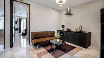 A modern living area with a sofa, a coffee table, a kitchen area with a sink and cabinets, and a hallway leading to another room.